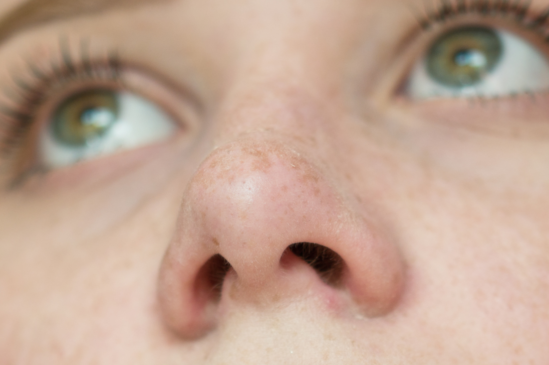 A close-up of a young woman's nose and septum.