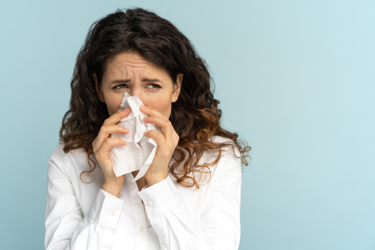 A frustrated woman with chronic rhinorrhea blows her nose.