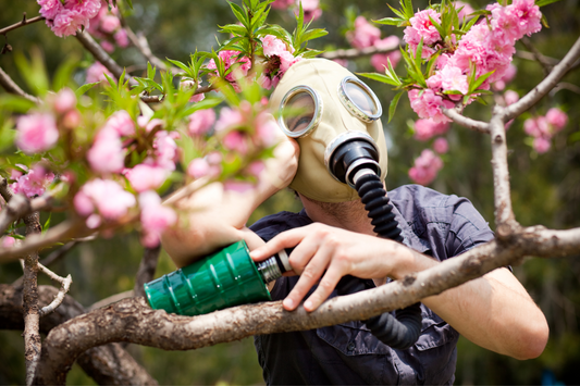 A man wearing a gas mask during allergy season surrounded by flowers.