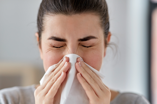 A woman blowing her nose too hard into a tissue.