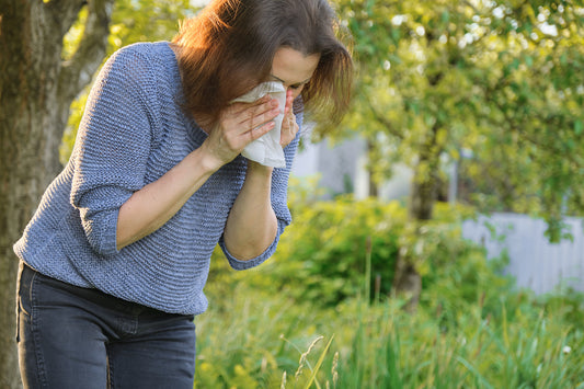 A woman with hay fever sneezing into a handkerchief.