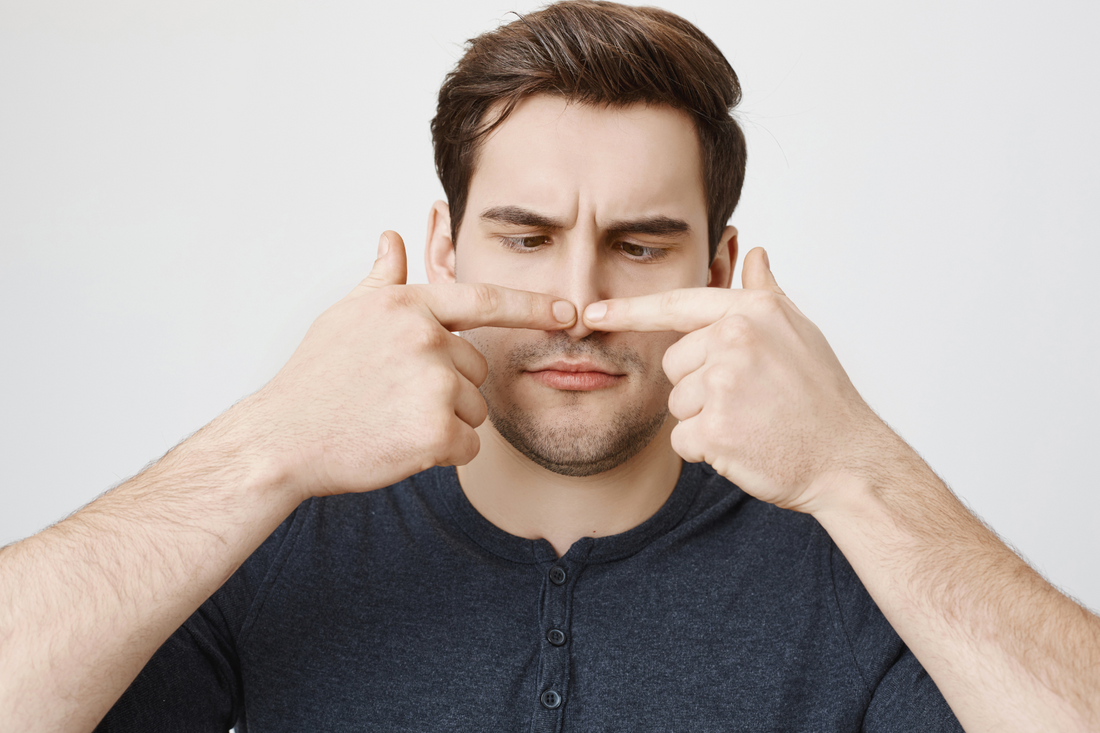 A young man checking for nasal polyps with two fingers.