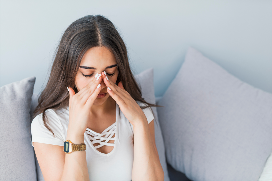 A young woman with a sinus headache with her hands on her nose.