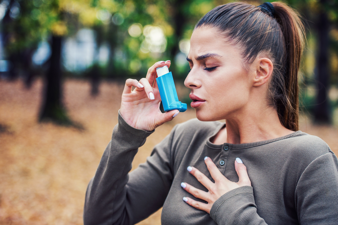 A young woman with asthma using an inhaler.