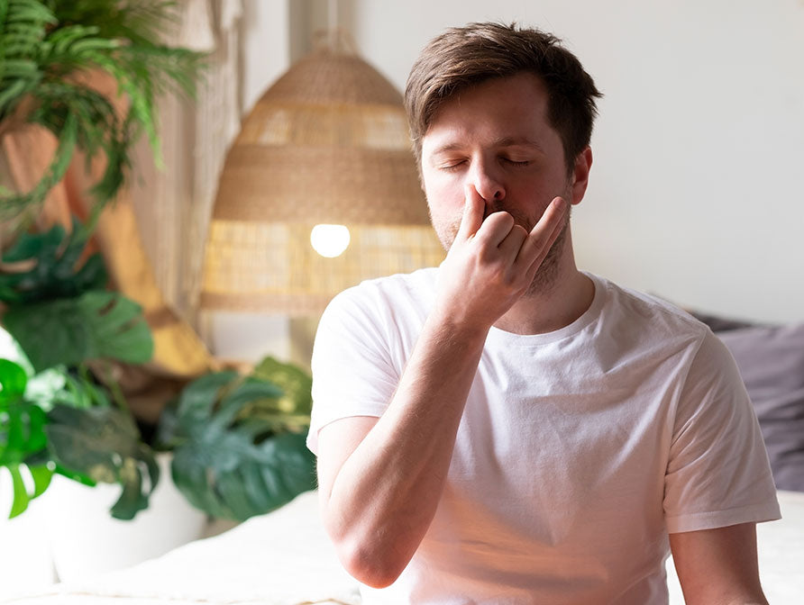 Young man sitting on his bed practicing nasal breathing