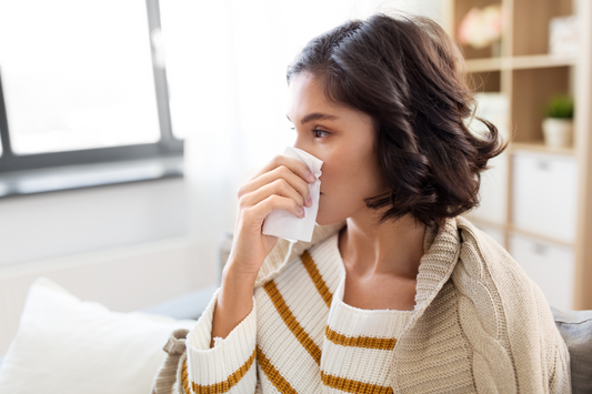 A young woman with nasal congestion carefully blowing her nose.